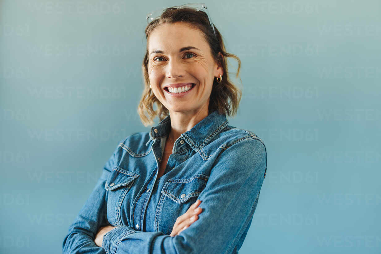 Happy and successful business woman looking at the camera in a studio. Female entrepreneur radiating confidence and professionalism while standing with her arms crossed.